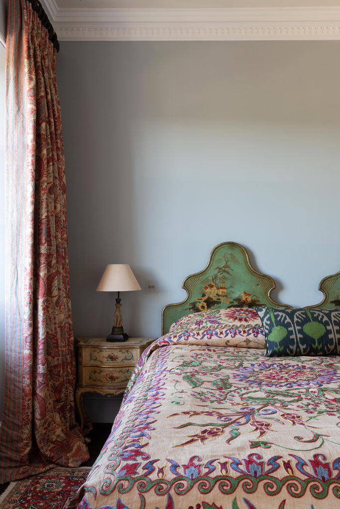 View of the luxurious hand-woven Silk Ikat  - Green Pomegranate cushion on a bed.