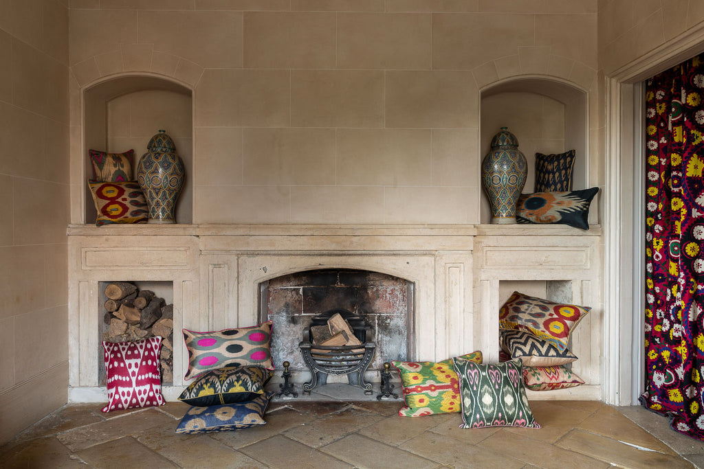 Image of fireplace surrounded by luxurious Silk Ikat cushions of various colours. 