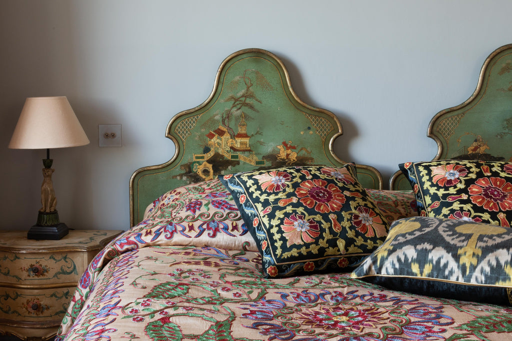 View of many hand-woven and hand-embroidered Silk Ikat cushions on a bed.