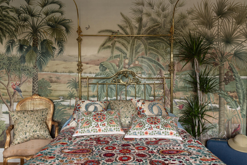 Hand-embroidered Green Pomegranate Vine Silk cushions displayed on a bed in a luxuriously designed room.  