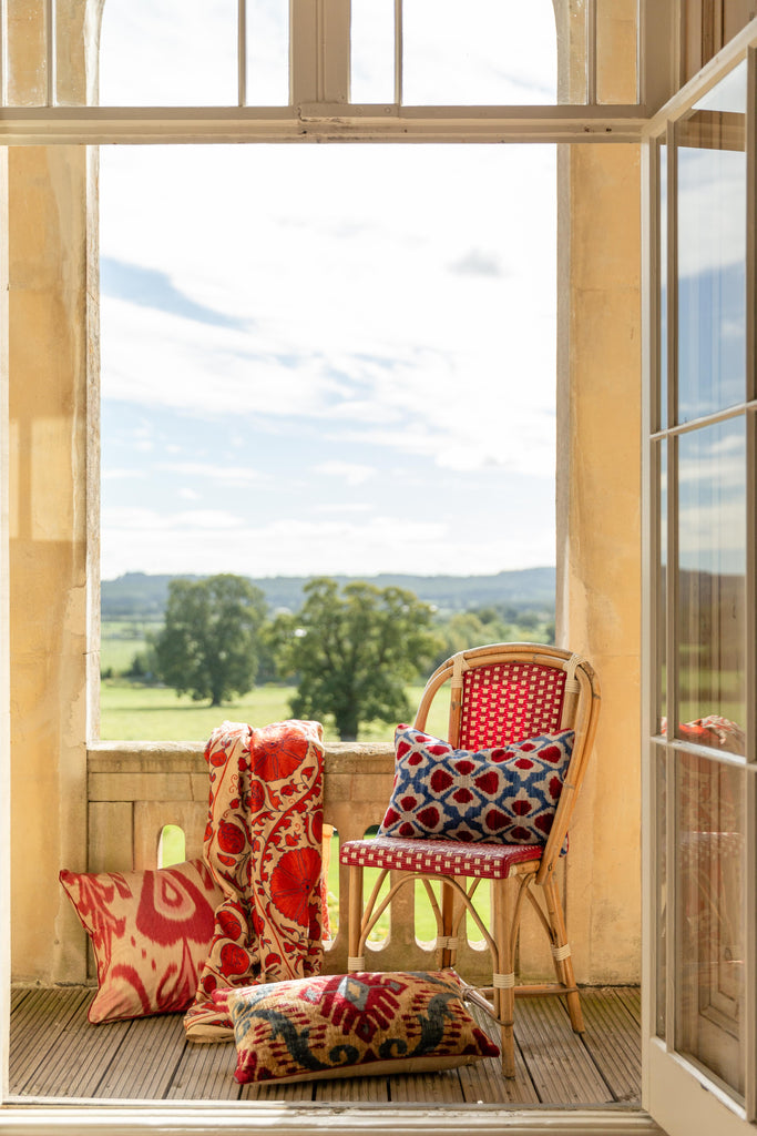 Beautiful view of the luxurious hand-woven Silk Velvet Ikat cushions on a chair next to a window in the countryside.